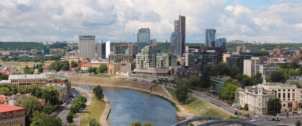 Panoramic view of Vilnius from above, showing the Neris River and the financial district with modern buildings and skyscrapers.
